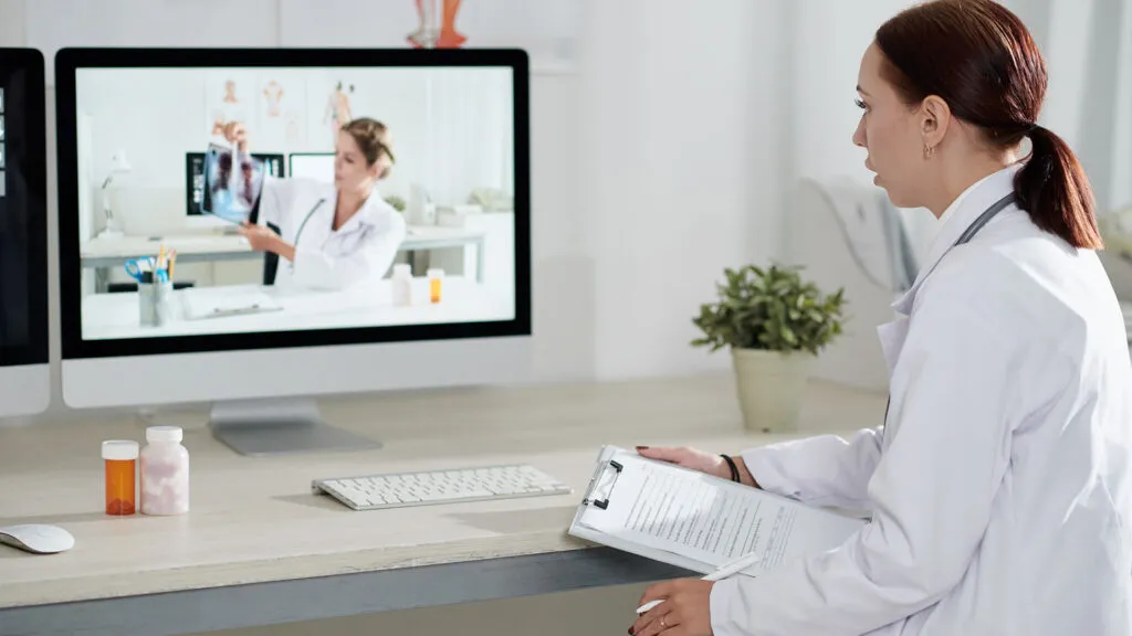 Una profesional de salud conversa por videollamada con otra profesional que muestra una radiografía